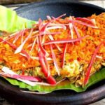 Foto hidangan Ikan Arsik yang siap disajikan, menampilkan ikan mas yang telah dibumbui dengan andaliman dan kunyit, disajikan dalam mangkuk tradisional, menggambarkan penyajian khas Batak