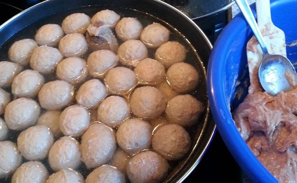 Proses pembuatan bakso sapi rumahan dengan adonan di baskom biru dan bakso direbus dalam panci besar berisi air panas